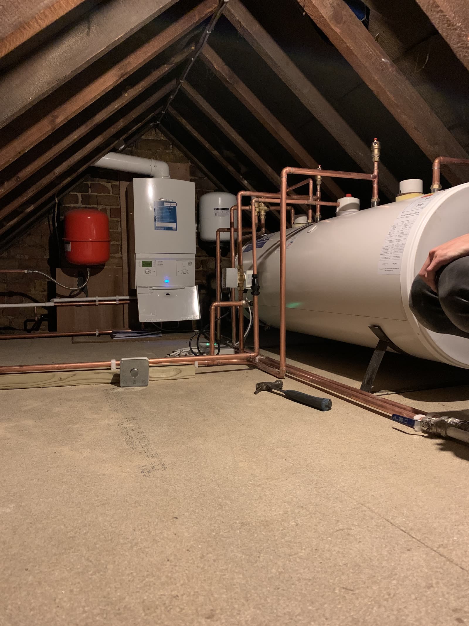A hot-water cylinder and copper pipework, run in tidily.